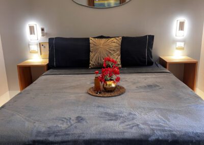 Straight view of floating queen bed with complimentary rum punch with flower arrangement with backlit mirror above.