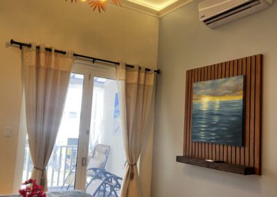 View of bed and locally designed light fitting with view of verandah in background.