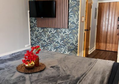 Bed with flowers and wall mounted TV in background.