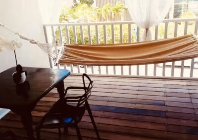 Hammock in verandah, next to two seater table with orchid.