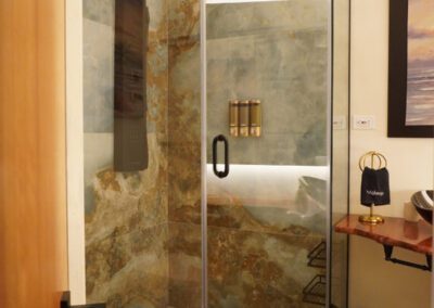 The shower has a full panel system with rainfall waterfall shower head, and massage body jets. Artisnal floor base made with locally sourced pebbles and marbled ocean coloured wall tiles.