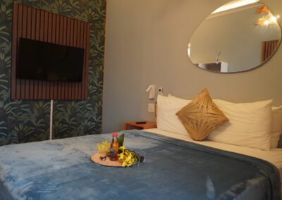 Side view of floating queen bed with complimentary rum punch with flower arrangement and mirror above.