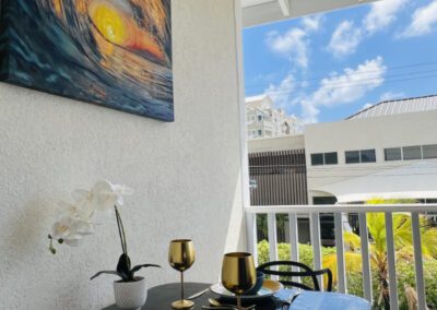 Two seater table set with crockery and two golden wine goblets and surfscape artwork above on wall.