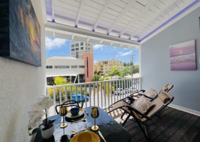 Verandah showing neighbourhood view with two fully reclining chair loungers, and two seater table set with crockery and two golden wine goblets.