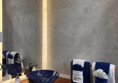 Blue glass basin with naturally cut polished wood vanity shelf in bathroom.