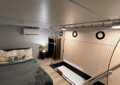 Loft bedroom showing bed and safety netting around the stairwell. All designed in a nautical theme.
