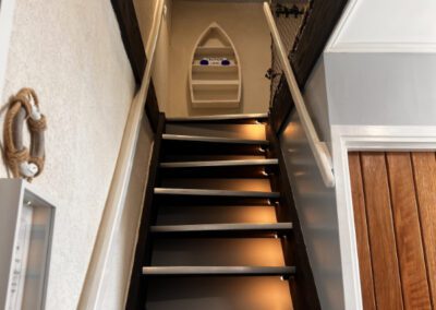 Stairs to loft showing quaint nautically-styled shelves at the top.