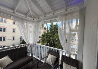 Verandah with two chairs and a two seater sofa decorated with cushions overlooking the neighbourhood.