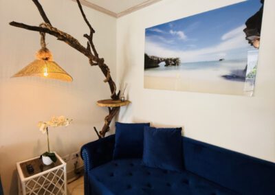 Large blue sofa with seascape artwork above, and a locally designed and made artisnal light feature.