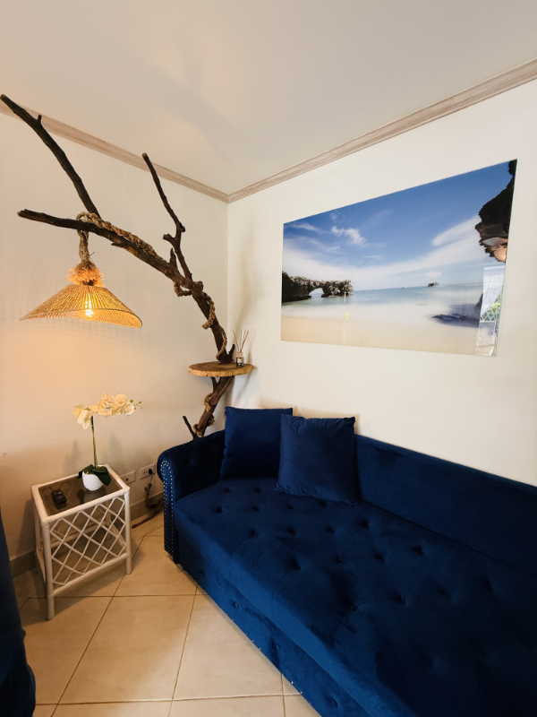 Large blue sofa with seascape artwork above, and a locally designed and made artisnal light feature.
