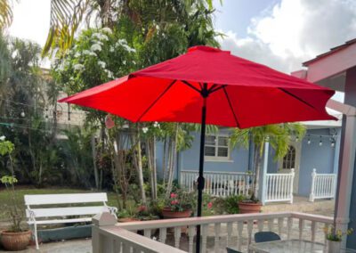 Rear garden patio with open sun umbrella and garden bench in background.