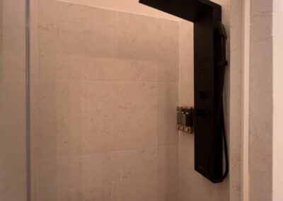 The shower has a full panel system with rainfall waterfall shower head, and massage body jets. Artisnal floor base made with locally sourced pebbles and neutral coloured wall tiles.
