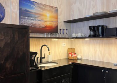 Kitchen sink and shelves fridge in the corner and complimentary tea and coffee on counter.