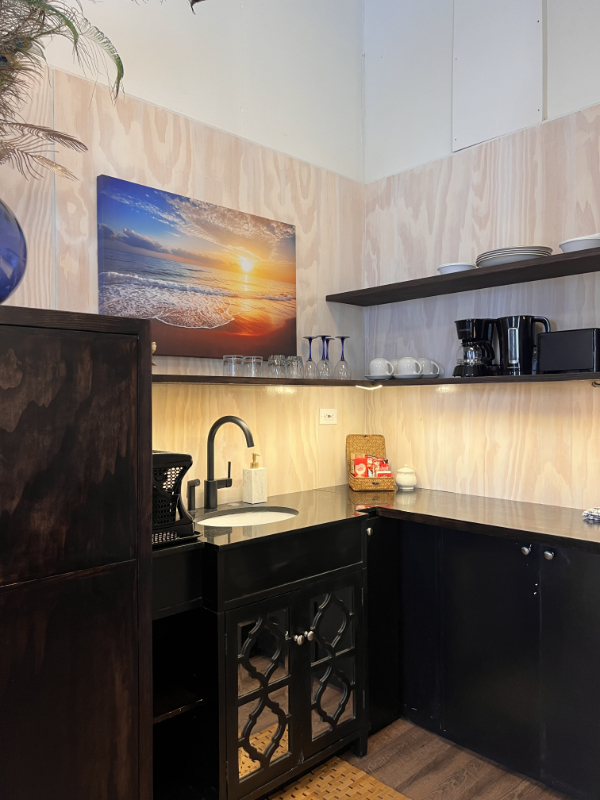 Kitchen sink and shelves fridge in the corner and complimentary tea and coffee on counter.