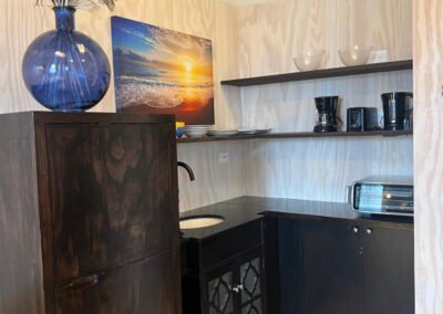 Kitchen counter and shelves showing toaster oven, sink, crockery, kettle, coffee maker and toaster.