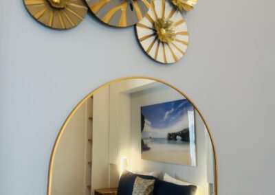Mirror reflecting view of bedroom with decorative artwork above.