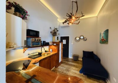 Kitchen showing microwave, toaster oven, hob, fridge, with crockery and complimentary tea / coffee. Futon nestled in hallway corner.