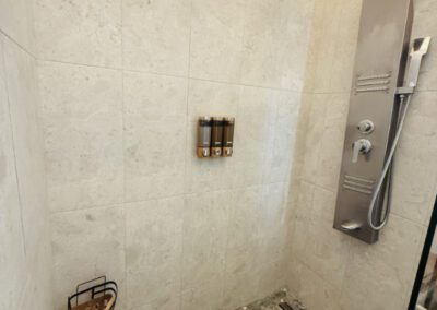 The shower has a full panel system with rainfall waterfall shower head, and massage body jets. Artisnal floor base made with locally sourced pebbles and neutral coloured wall tiles.